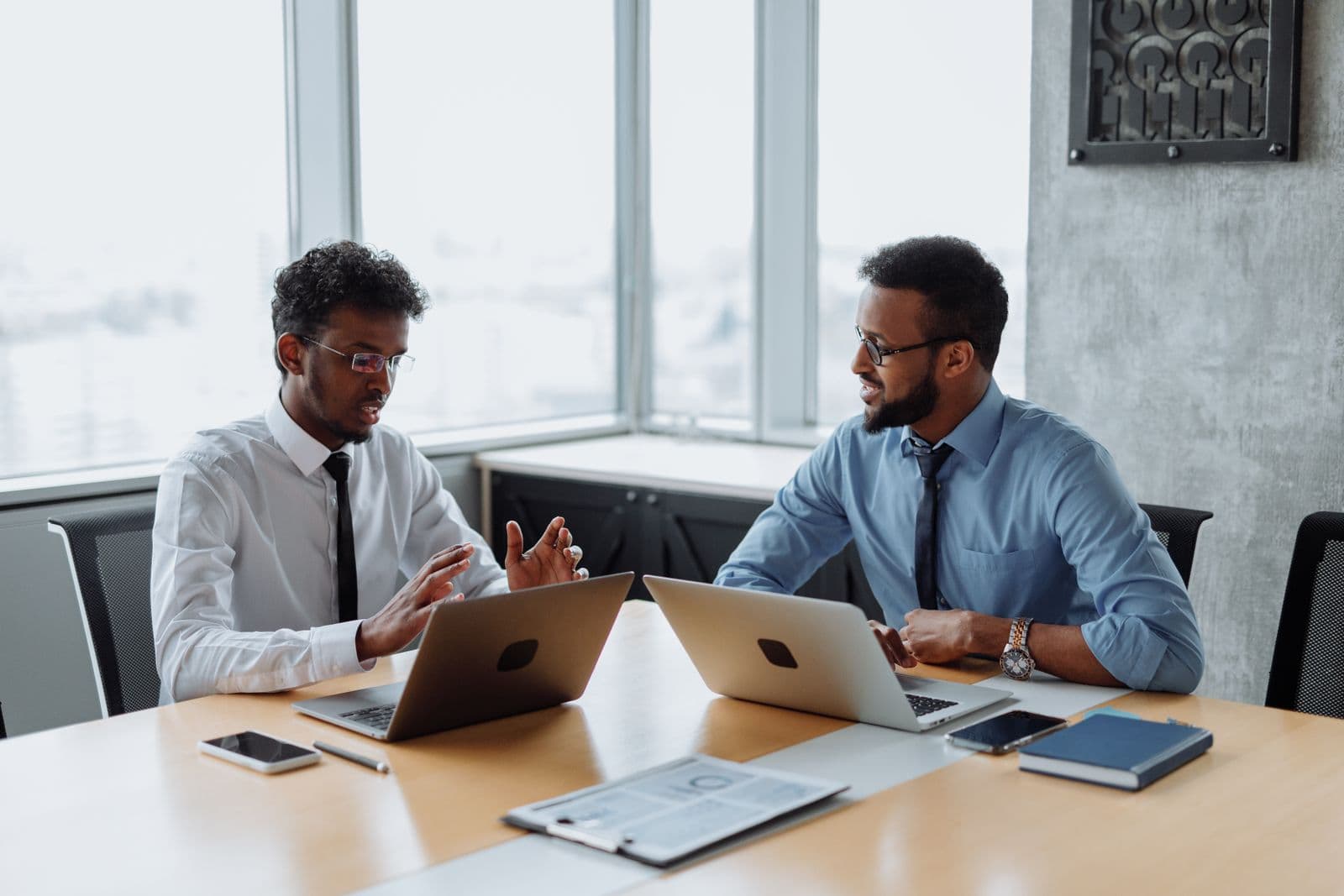 Two professionals planning a project together on their laptops