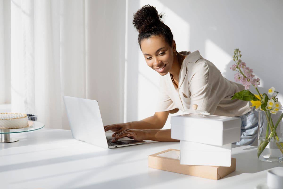 A small business owner smiling at her laptop beside packed orders