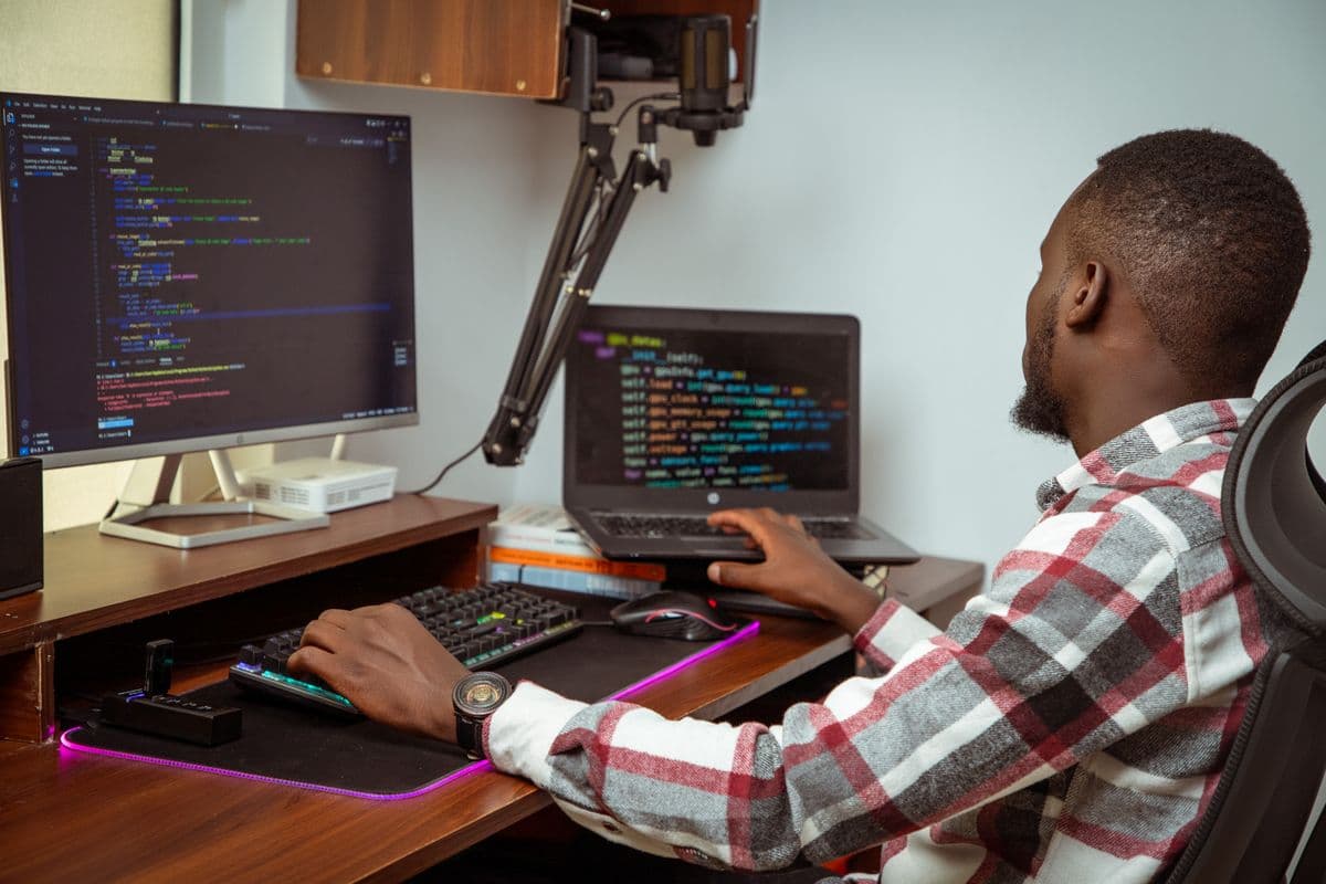 A developer in Nairobi working on code across two screens