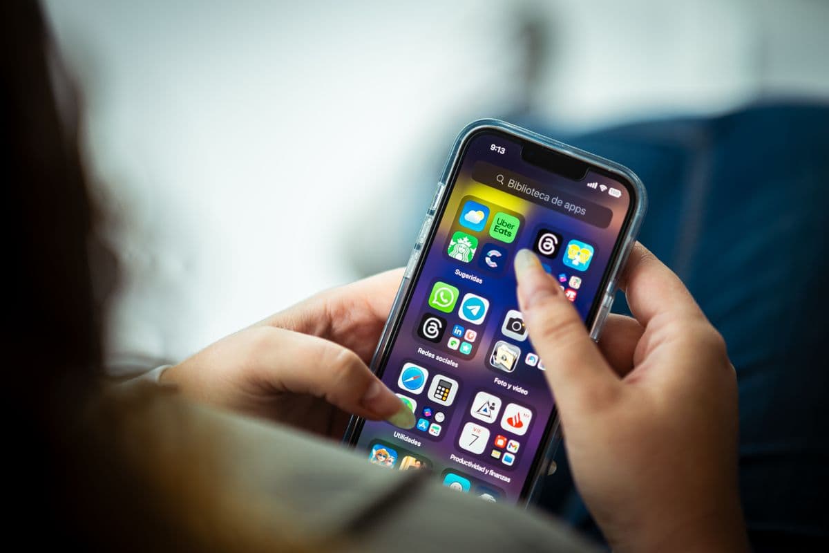 Hands holding a phone with a screen full of apps